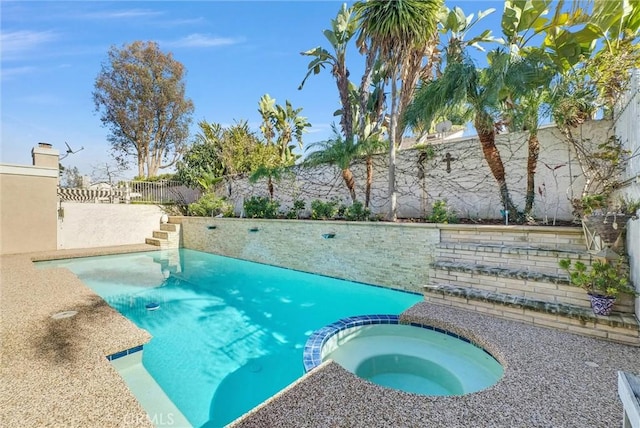 view of swimming pool featuring a fenced backyard and a pool with connected hot tub