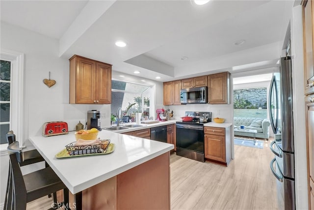 kitchen featuring stainless steel appliances, a wealth of natural light, a sink, and a peninsula