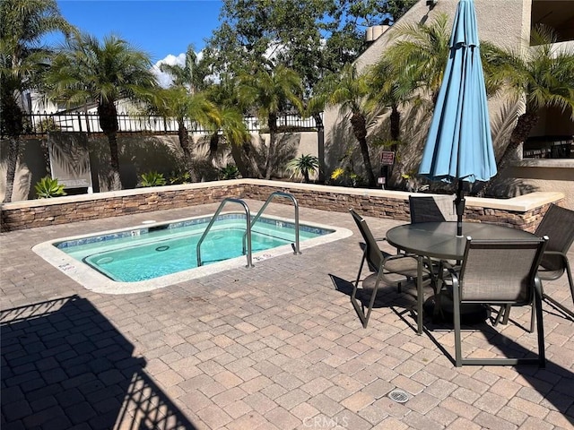 view of pool featuring outdoor dining space, fence, a community hot tub, and a patio