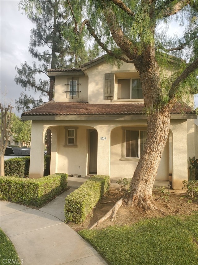 mediterranean / spanish house featuring covered porch, a tile roof, and stucco siding