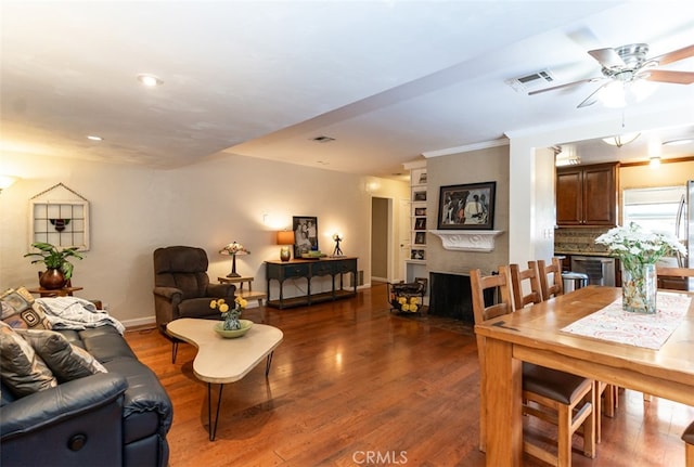 living room featuring baseboards, wood finished floors, visible vents, and a large fireplace