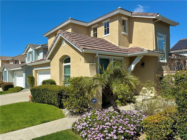 view of front of house featuring stucco siding, a garage, concrete driveway, and a tile roof