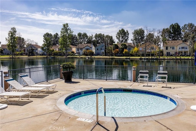 view of swimming pool with a water view, fence, a residential view, and a patio area