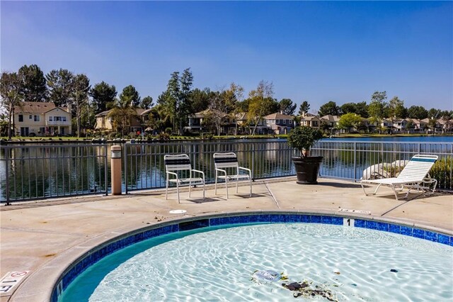 view of pool featuring a water view, a residential view, a patio, and fence