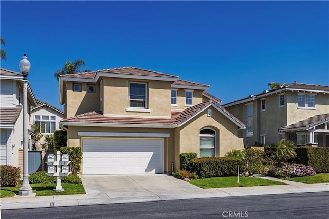 traditional-style home with an attached garage, a tiled roof, driveway, and stucco siding