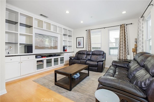 living room with light wood-style flooring, baseboards, visible vents, recessed lighting, and built in features