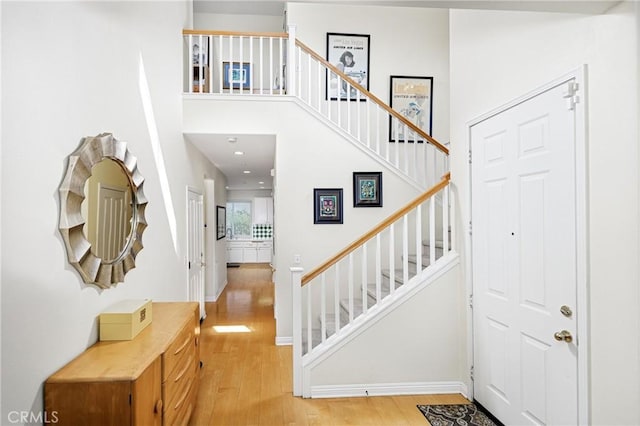 entryway featuring baseboards, wood finished floors, and stairs