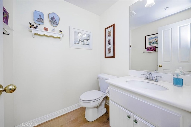 bathroom with baseboards, wood finished floors, toilet, and vanity