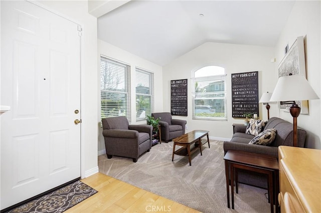 living room featuring lofted ceiling, baseboards, and wood finished floors