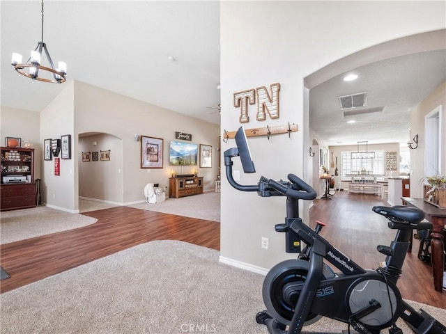 exercise room with baseboards, visible vents, arched walkways, wood finished floors, and a notable chandelier