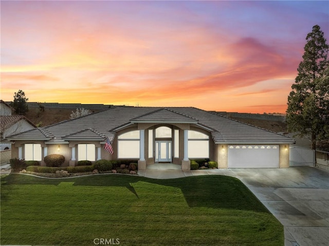 view of front of house featuring a yard, an attached garage, driveway, and stucco siding