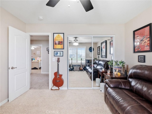 living area featuring ceiling fan, baseboards, and carpet flooring