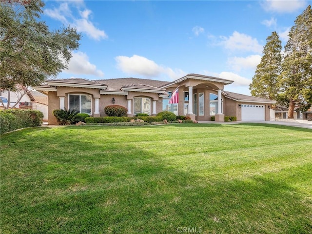 mediterranean / spanish home with a garage, stucco siding, driveway, and a front yard