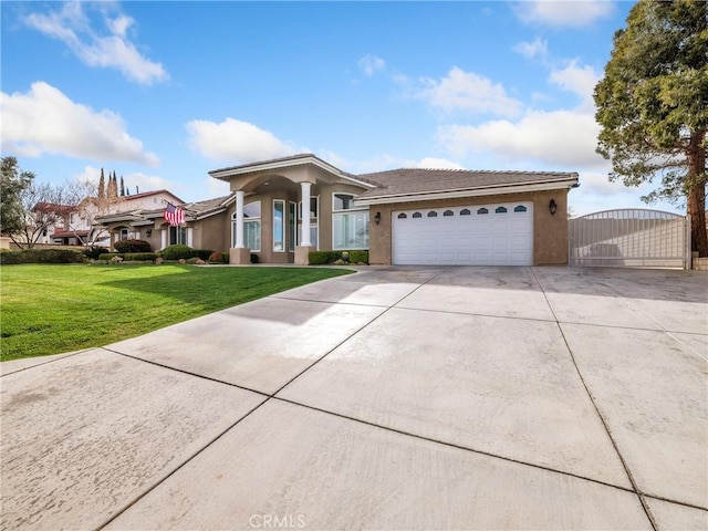 view of front of home with stucco siding, concrete driveway, an attached garage, a gate, and a front lawn