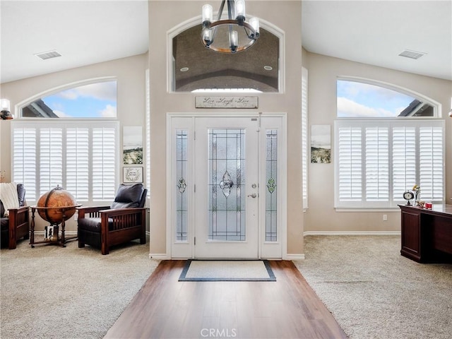 foyer with a chandelier, visible vents, and wood finished floors