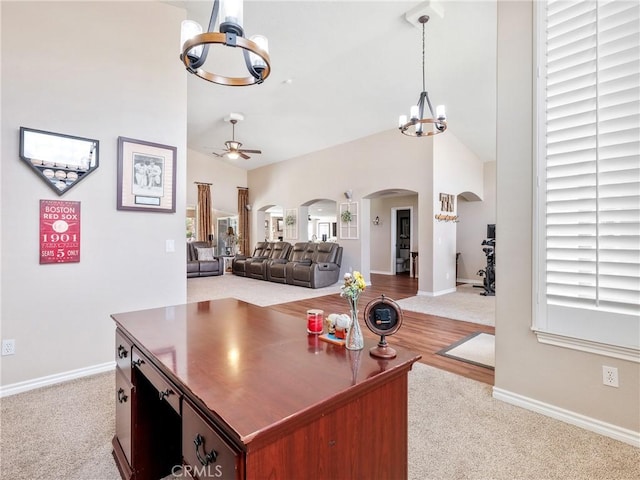 interior space with high vaulted ceiling, arched walkways, carpet floors, and ceiling fan with notable chandelier