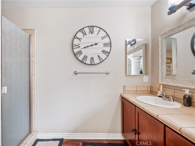 bathroom featuring vanity, a shower with door, and baseboards