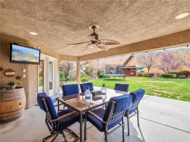 view of patio / terrace with a trampoline, outdoor dining area, and ceiling fan