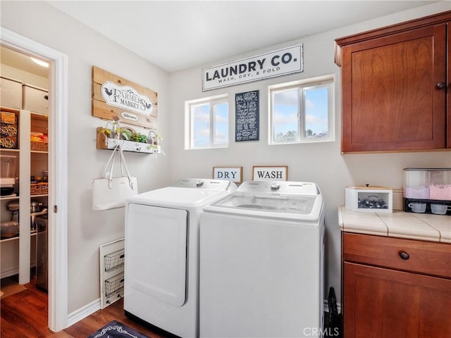 laundry room with cabinet space, dark wood finished floors, washer and clothes dryer, and a wealth of natural light