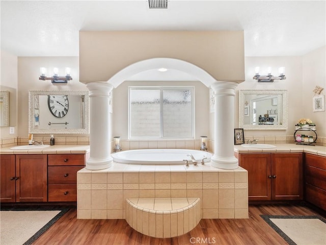 bathroom with a sink, ornate columns, and wood finished floors