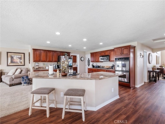 kitchen with recessed lighting, stainless steel appliances, a breakfast bar, dark wood-style flooring, and light stone countertops