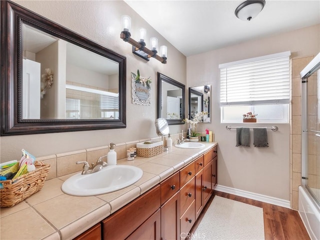 bathroom with double vanity, a sink, baseboards, and wood finished floors