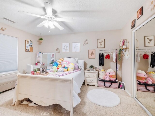 bedroom with ceiling fan, a textured ceiling, carpet, and visible vents