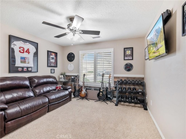 living area with a textured ceiling, carpet flooring, visible vents, baseboards, and a ceiling fan