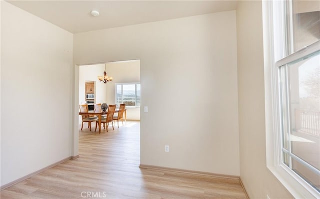 empty room featuring light wood-style floors and an inviting chandelier