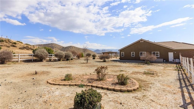 view of yard with a rural view, fence, and a mountain view