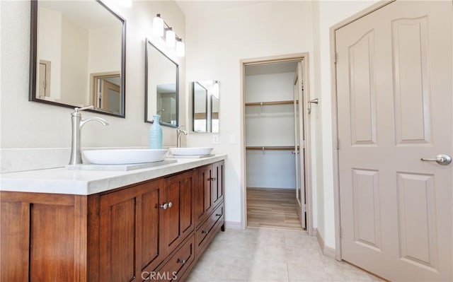 bathroom with double vanity, tile patterned flooring, a spacious closet, and a sink