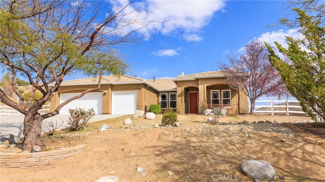 view of front of home with a garage, driveway, a tile roof, and stucco siding