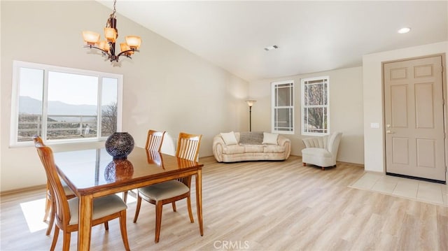 dining room featuring lofted ceiling, a mountain view, light wood-style flooring, and a notable chandelier