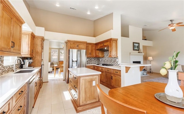 kitchen featuring a center island, stainless steel appliances, light countertops, a sink, and under cabinet range hood