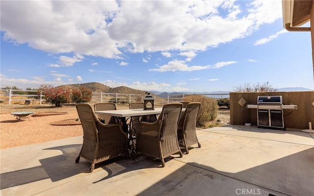 view of patio featuring a mountain view, fence, grilling area, and outdoor dining space