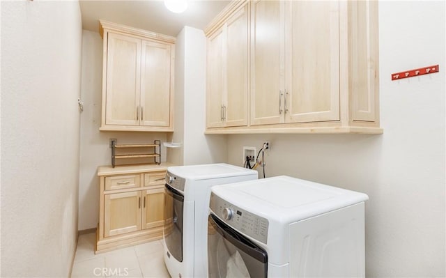 washroom featuring cabinet space, light tile patterned flooring, and washing machine and clothes dryer