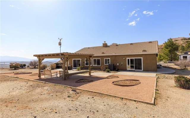 rear view of house with a patio, a chimney, a pergola, cooling unit, and a tiled roof