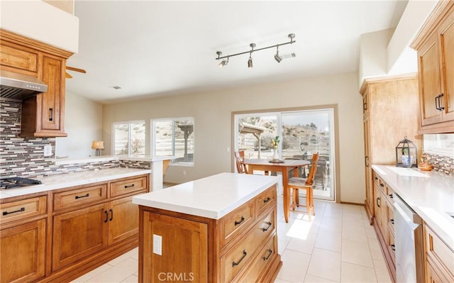 kitchen featuring decorative backsplash, a kitchen island, stainless steel appliances, light countertops, and under cabinet range hood