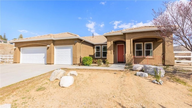 view of front of property with concrete driveway, fence, a tiled roof, and an attached garage