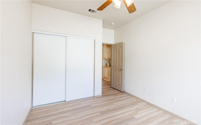 unfurnished bedroom with light wood-style flooring, visible vents, ceiling fan, and a closet