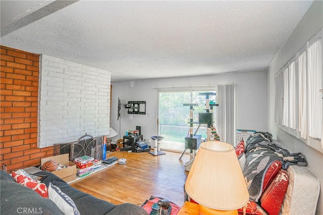 living area with a fireplace, a textured ceiling, and wood finished floors