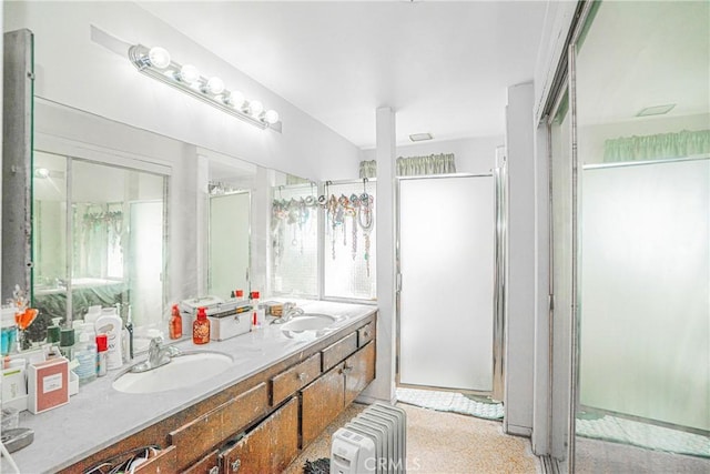 bathroom featuring double vanity, a wealth of natural light, radiator heating unit, and a sink