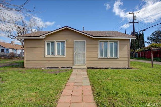 view of front of house featuring a shingled roof and a front lawn