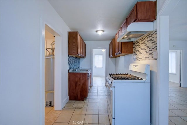 kitchen featuring light tile patterned floors, under cabinet range hood, decorative backsplash, and white gas range oven