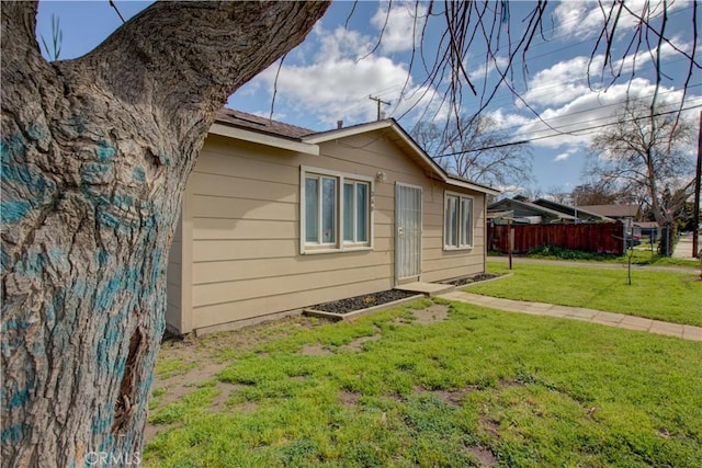 view of side of property with a lawn and fence