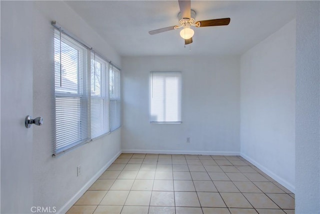 empty room with ceiling fan, baseboards, and light tile patterned floors