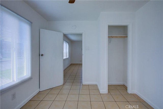 unfurnished bedroom featuring light tile patterned floors, ceiling fan, a closet, and baseboards