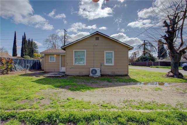 rear view of property featuring a yard, ac unit, and fence