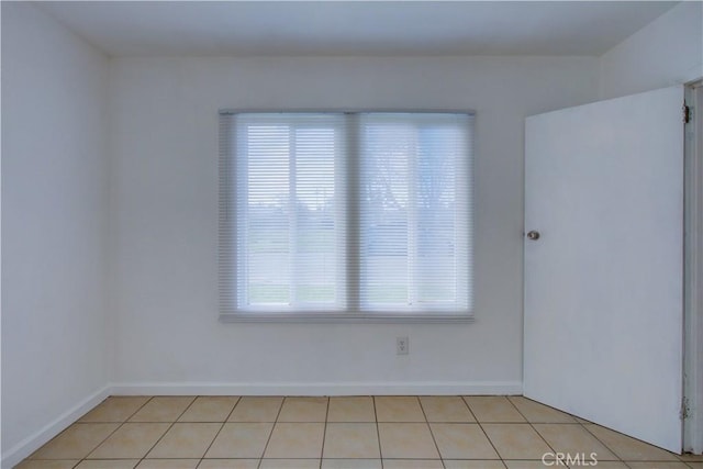 spare room featuring baseboards and light tile patterned floors