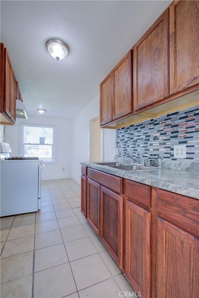 kitchen with light tile patterned floors, white range with gas stovetop, decorative backsplash, light countertops, and under cabinet range hood